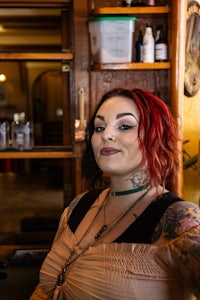 a woman with red hair and tattoos standing in front of a bar